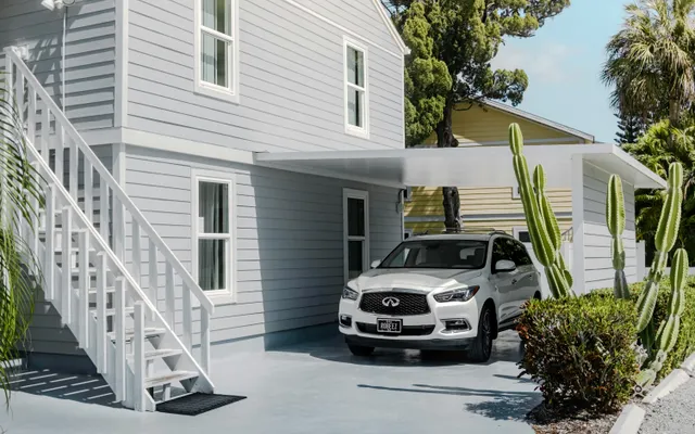 Carport en aluminium à toit plat le long d’une maison, une voiture garée dessous