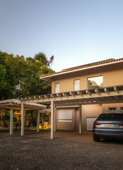 Carport aluminium double à claire-voie devant une maison à étage, véhicule garé au crépuscule