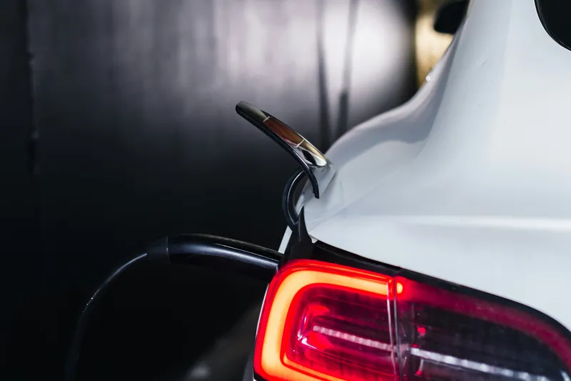 Véhicule électrique en charge sous un carport équipé d'une borne de recharge murale
