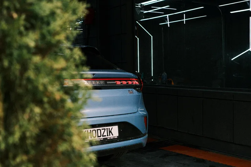 Véhicule électrique en charge sous un carport équipé de panneaux solaires