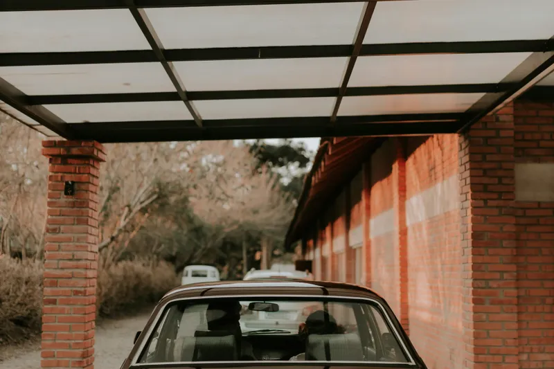 Carport en aluminium à toit plat abritant une voiture devant une maison contemporaine