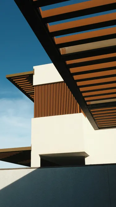 Vue en contre-plongée sur les lames orientables en aluminium d'une pergola bioclimatique
