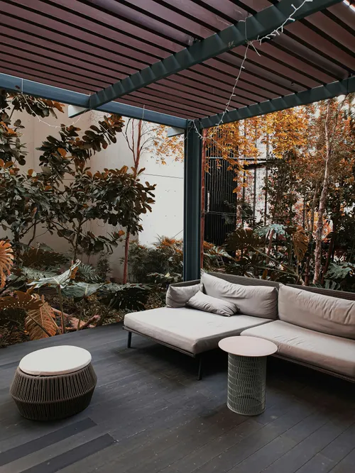 Pergola classique à toit fixe en bois foncé au-dessus d'un salon de jardin extérieur