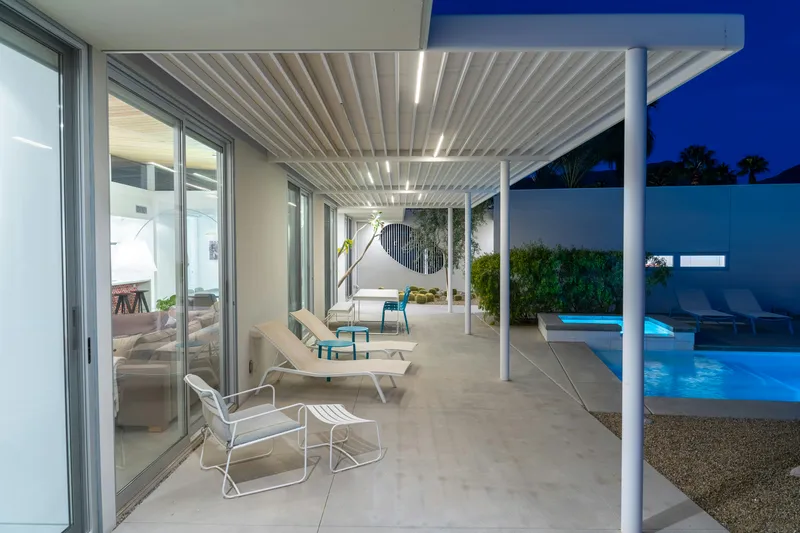 Pergola avec éclairage LED intégré au bord d'une piscine, ambiance nocturne haut de gamme